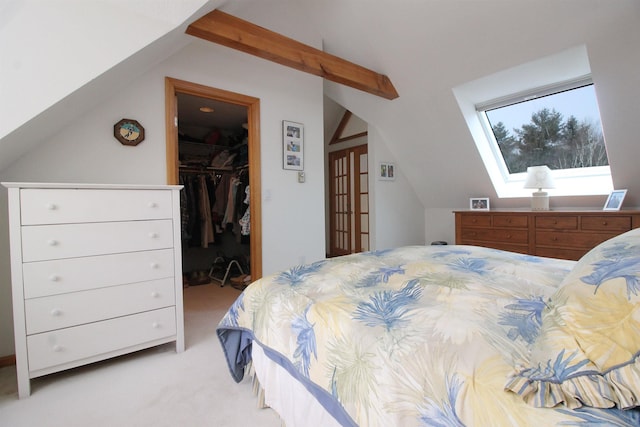 bedroom with a closet, light carpet, a spacious closet, and vaulted ceiling with skylight