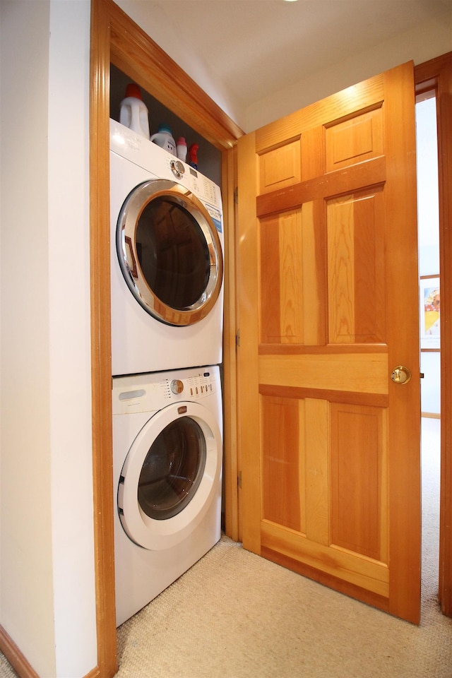 laundry area with laundry area, stacked washer and dryer, and carpet floors