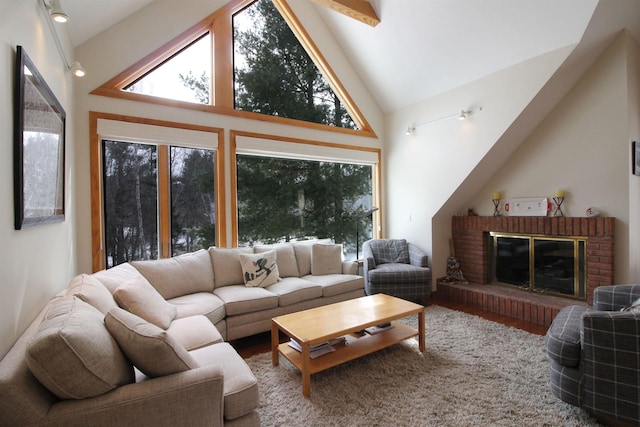 living room with a brick fireplace, wood finished floors, and high vaulted ceiling