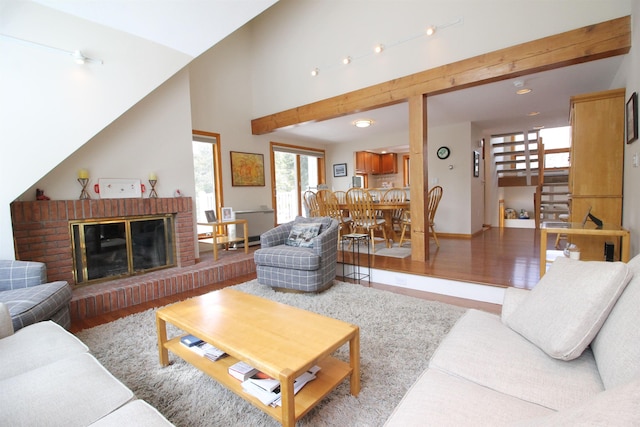 living room with baseboards, stairway, a fireplace, a high ceiling, and wood finished floors