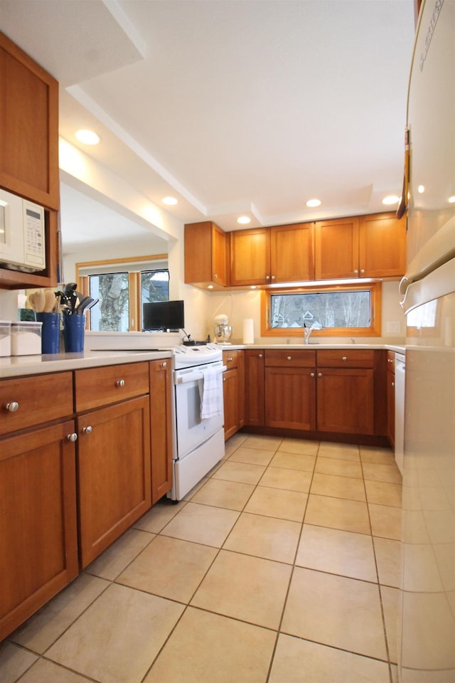 kitchen with white microwave, light countertops, light tile patterned floors, recessed lighting, and brown cabinets