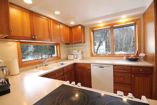 kitchen with a sink, dishwasher, brown cabinetry, and light countertops