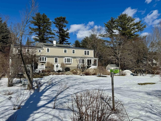 snow covered house featuring a chimney