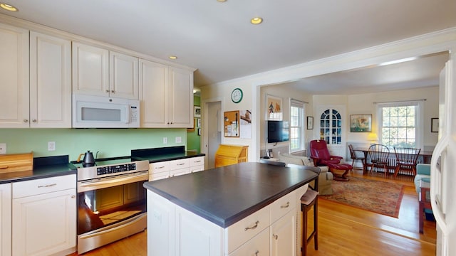 kitchen with white appliances, light wood-style flooring, white cabinetry, dark countertops, and open floor plan