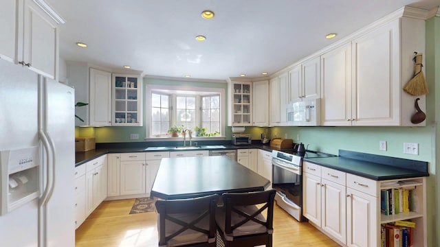 kitchen with dark countertops, light wood-style flooring, and white appliances