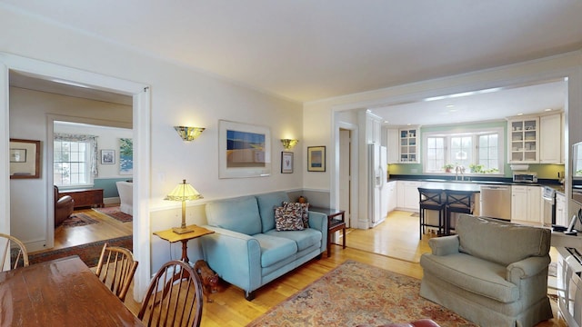 living room with light wood-style flooring, a toaster, and ornamental molding