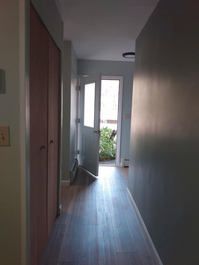 hallway with a baseboard radiator, baseboards, and wood finished floors