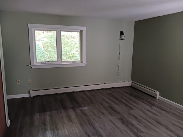 spare room featuring wood finished floors, baseboards, and baseboard heating