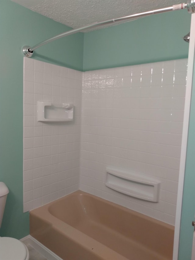 full bathroom with bathing tub / shower combination, toilet, and a textured ceiling