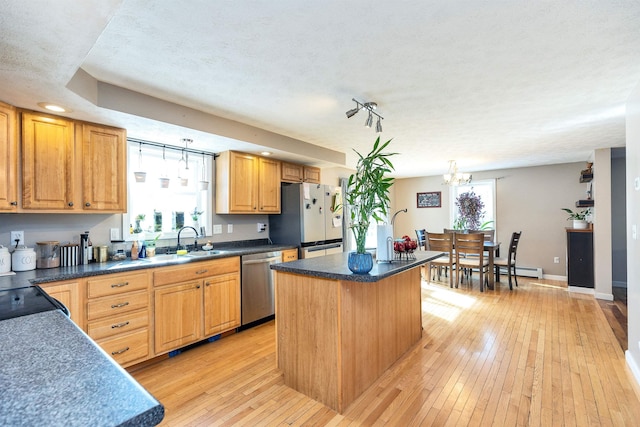 kitchen featuring light wood finished floors, freestanding refrigerator, a sink, stainless steel dishwasher, and a center island