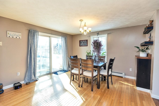 dining room with a baseboard heating unit, baseboards, an inviting chandelier, light wood-style floors, and a textured ceiling