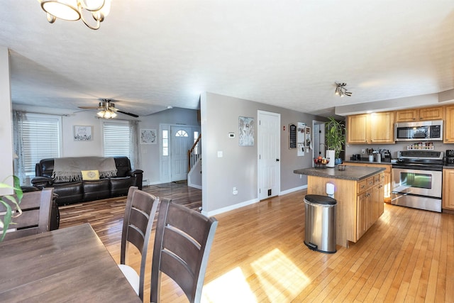 kitchen with dark countertops, open floor plan, light wood-type flooring, and stainless steel appliances