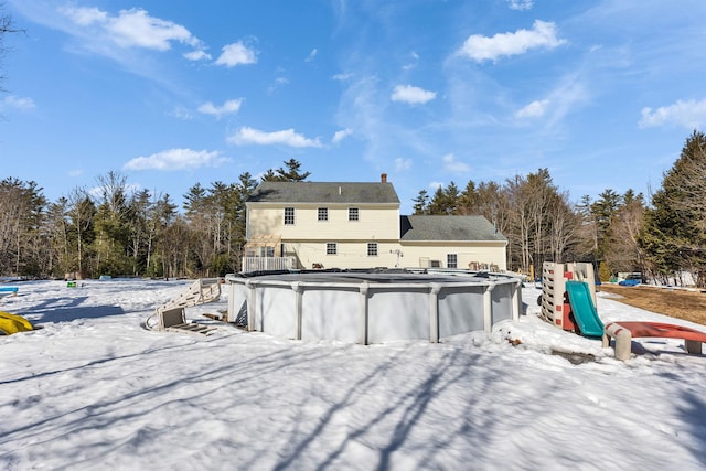 snow covered property with a covered pool and a playground