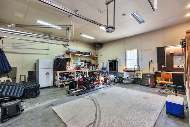 garage featuring a workshop area, a garage door opener, and freestanding refrigerator