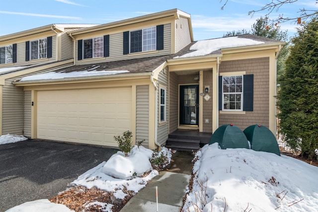 view of front of home featuring aphalt driveway, an attached garage, and roof with shingles