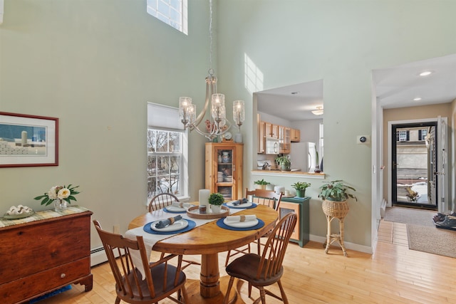 dining room featuring a wealth of natural light, light wood-style floors, baseboards, and a notable chandelier