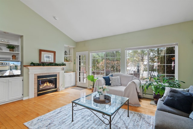 living room with light wood finished floors, a fireplace, built in shelves, and a baseboard radiator