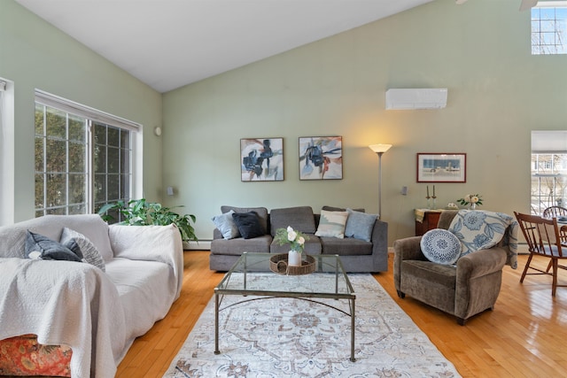 living area featuring a baseboard heating unit, a wall unit AC, light wood-style flooring, and high vaulted ceiling