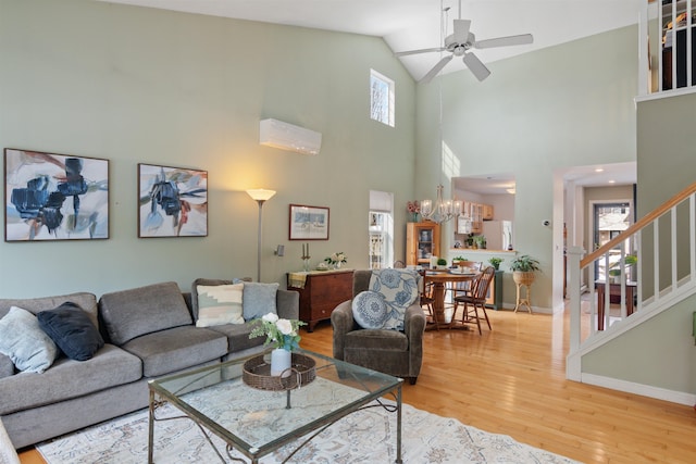 living room featuring ceiling fan with notable chandelier, light wood-style floors, a healthy amount of sunlight, and a wall mounted AC