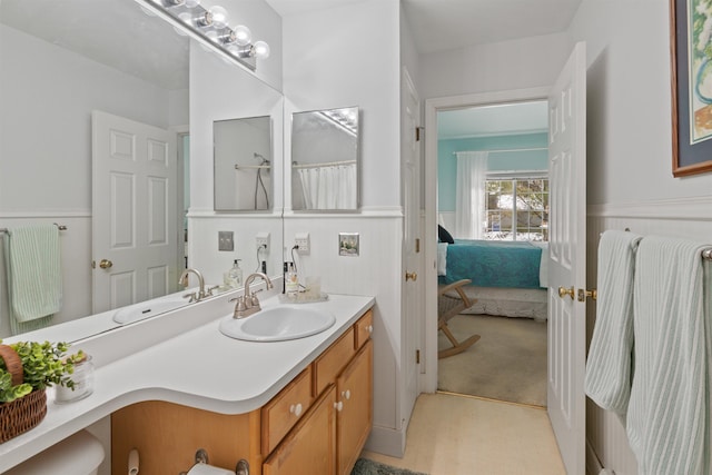 ensuite bathroom with a wainscoted wall, connected bathroom, and vanity