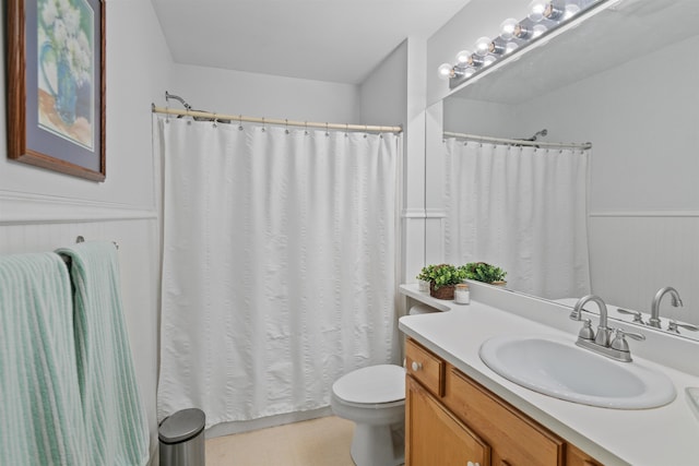 bathroom featuring a shower with curtain, vanity, toilet, and wainscoting