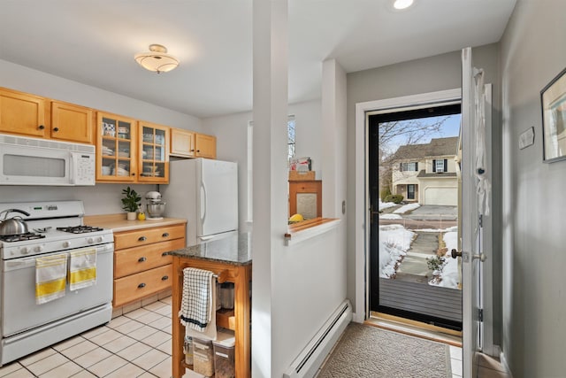 kitchen featuring glass insert cabinets, dark stone counters, baseboard heating, light tile patterned flooring, and white appliances