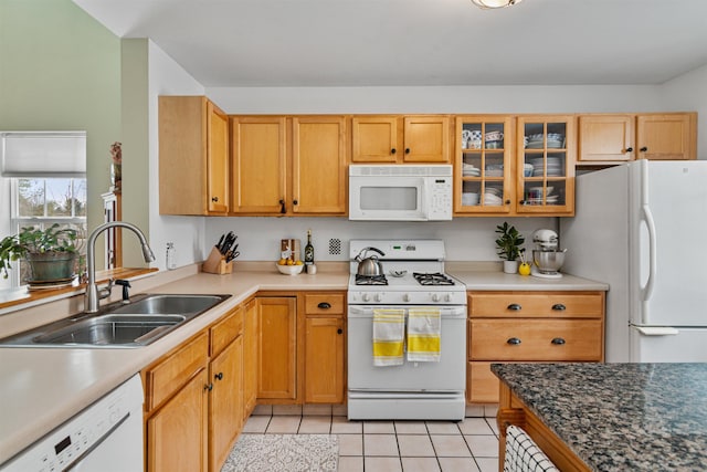 kitchen with a sink, glass insert cabinets, white appliances, and light tile patterned floors