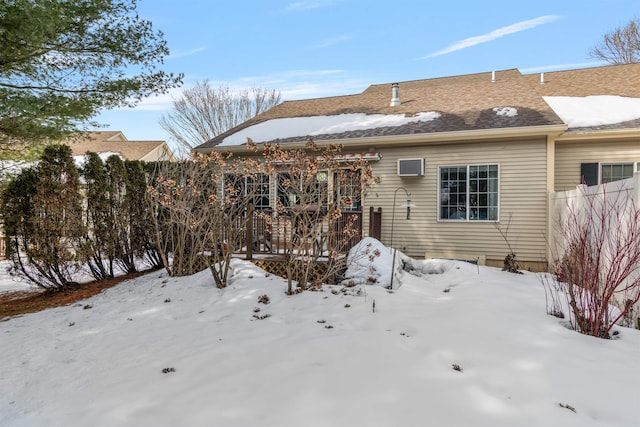 snow covered rear of property with a deck and fence