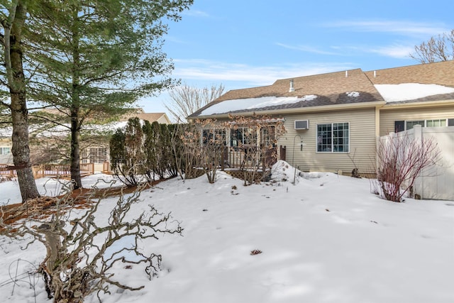 snow covered rear of property featuring fence, a wall mounted air conditioner, and a wooden deck