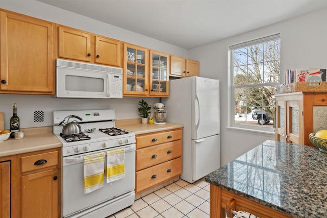 kitchen with light tile patterned flooring, a healthy amount of sunlight, white appliances, and glass insert cabinets