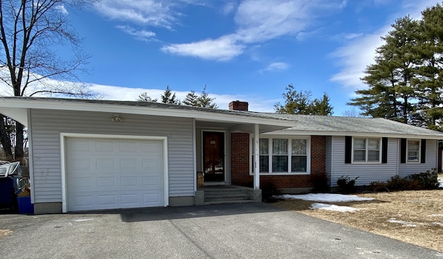 single story home with brick siding, an attached garage, a chimney, and aphalt driveway