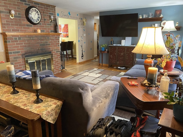 living room featuring a brick fireplace, baseboards, and wood finished floors