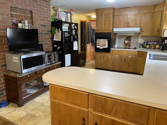 kitchen with under cabinet range hood, black appliances, light countertops, and a sink