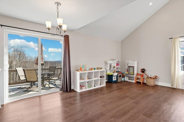 rec room featuring baseboards, wood finished floors, an inviting chandelier, and vaulted ceiling