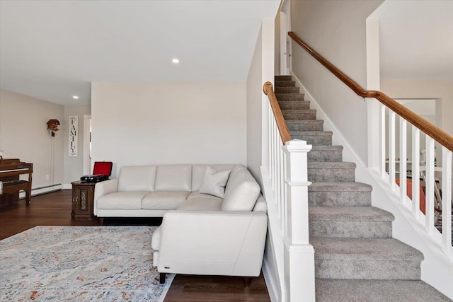 living area with recessed lighting, a baseboard heating unit, wood finished floors, and stairs