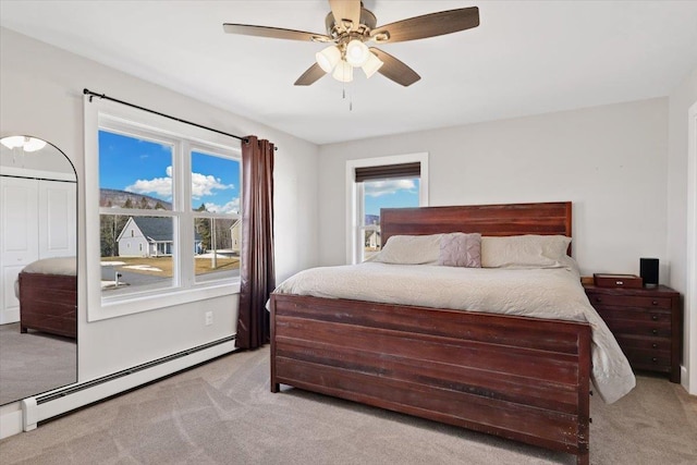 carpeted bedroom with a baseboard heating unit and ceiling fan