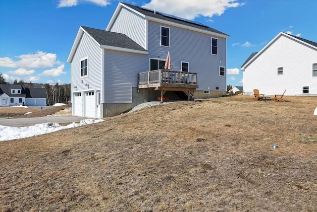 rear view of house featuring roof mounted solar panels, a wooden deck, and a garage