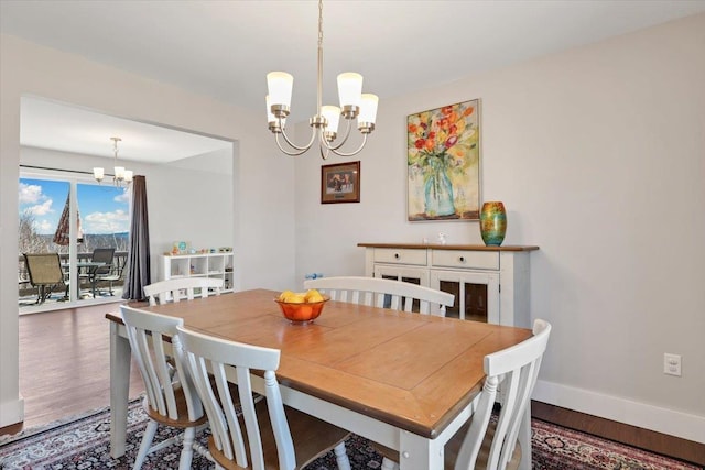 dining room with baseboards, an inviting chandelier, and wood finished floors