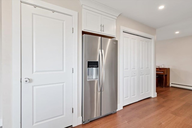 kitchen featuring recessed lighting, light wood-style flooring, stainless steel fridge, white cabinetry, and a baseboard radiator