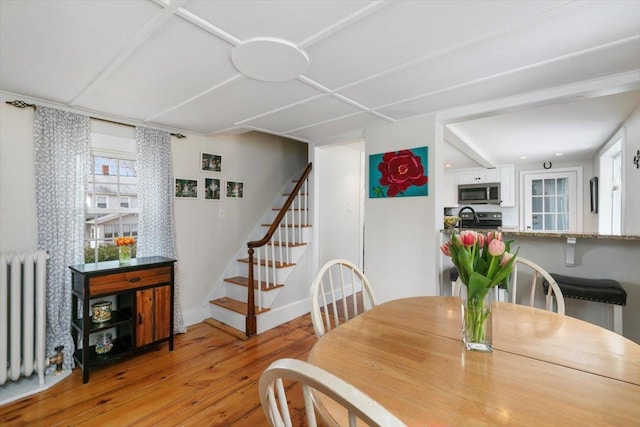 dining area with stairway, radiator, light wood-style flooring, and baseboards