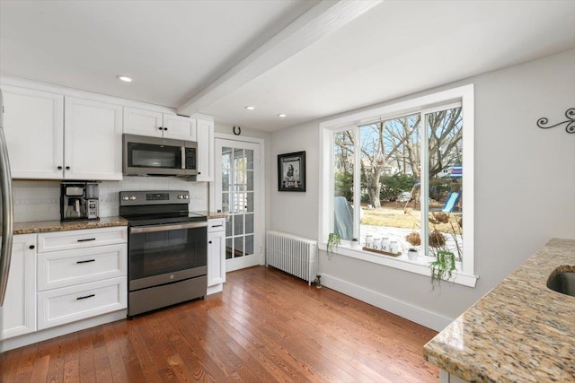 kitchen featuring tasteful backsplash, radiator, appliances with stainless steel finishes, and dark wood-style flooring