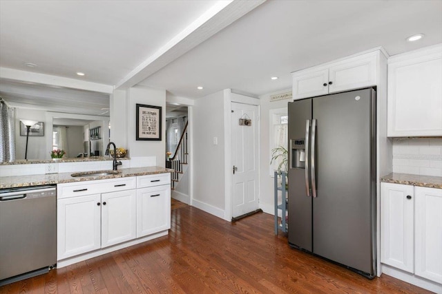 kitchen with a sink, dark wood finished floors, white cabinetry, stainless steel appliances, and light stone countertops