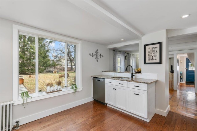 kitchen featuring a sink, stainless steel dishwasher, radiator heating unit, light stone countertops, and dark wood-style flooring