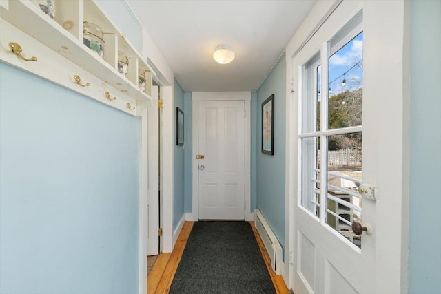 entryway featuring light wood finished floors, a baseboard heating unit, and baseboards