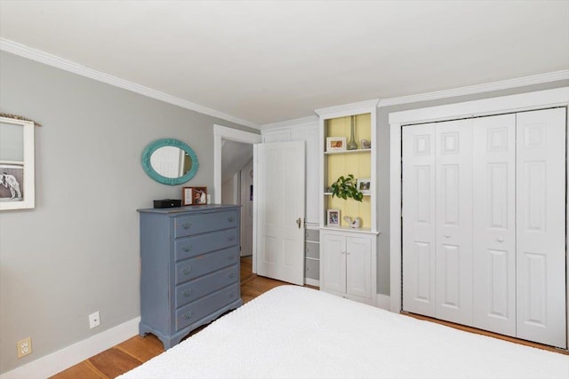 bedroom with a closet, ornamental molding, baseboards, and wood finished floors