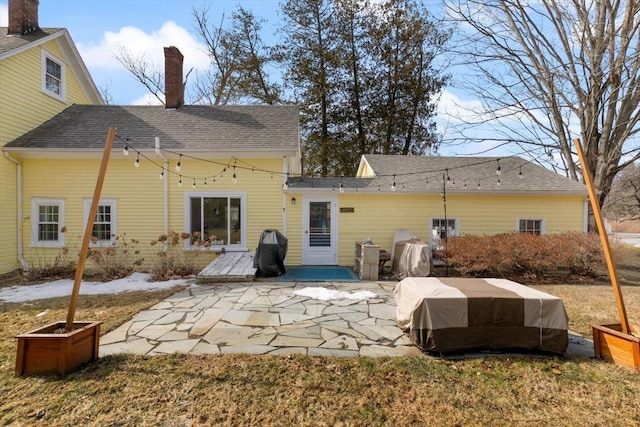 rear view of house featuring a shingled roof and a patio