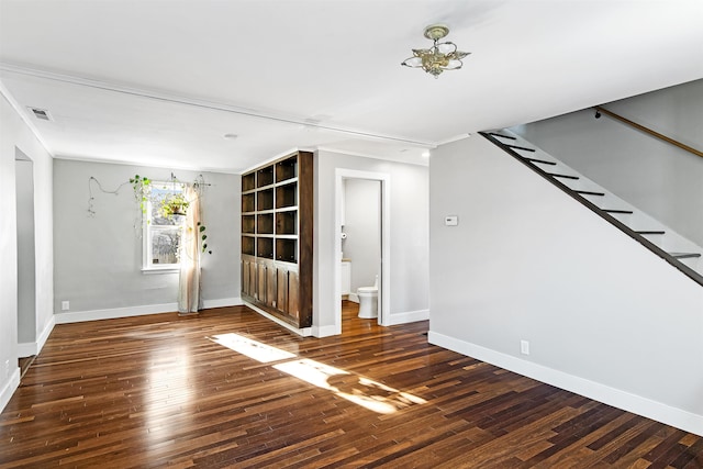 unfurnished room featuring visible vents, baseboards, hardwood / wood-style floors, and stairway