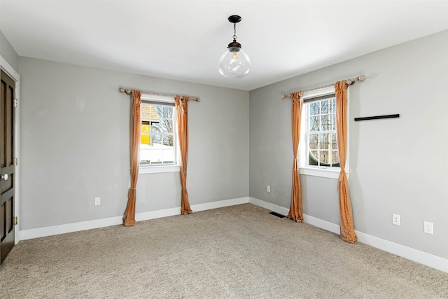 empty room with a healthy amount of sunlight, light colored carpet, and baseboards