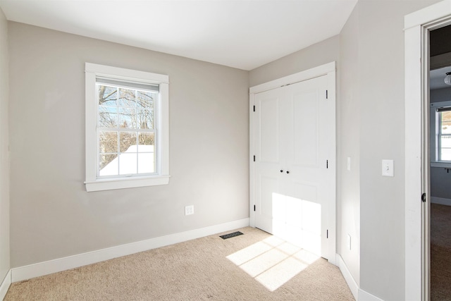 unfurnished bedroom with visible vents, baseboards, carpet, and a closet