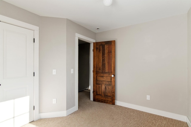 unfurnished bedroom featuring light colored carpet and baseboards